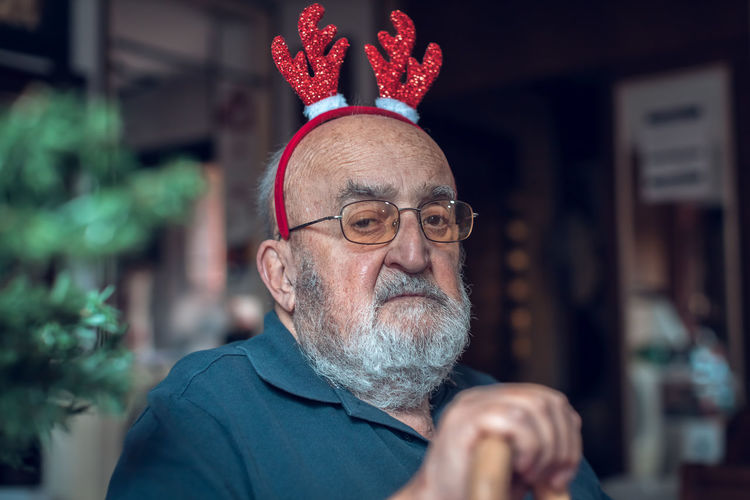 Portrait of depressed elderly man with reindeer ears