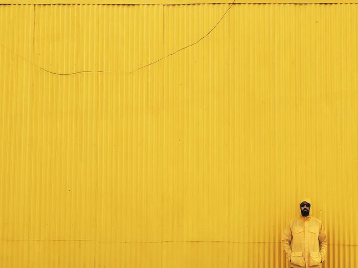 Portrait of man standing against of yellow wall