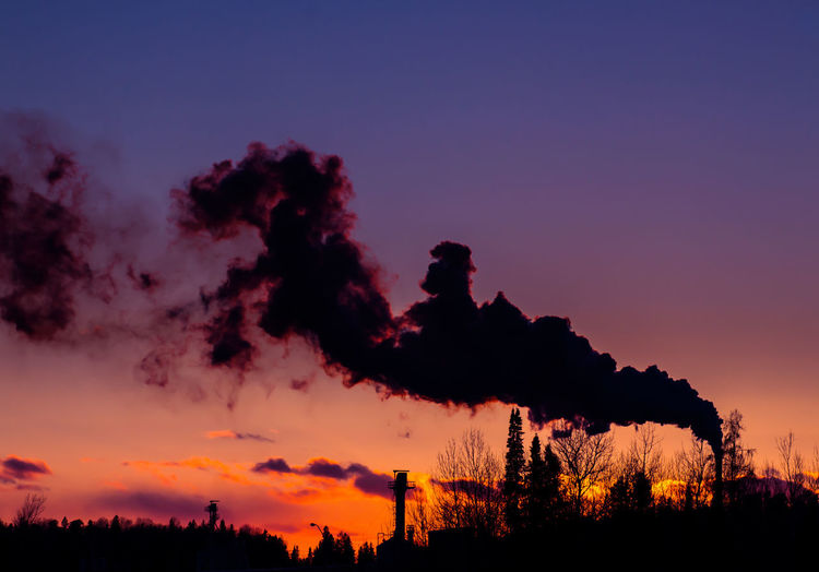 Smoke emerging from chimney on silhouette landscape