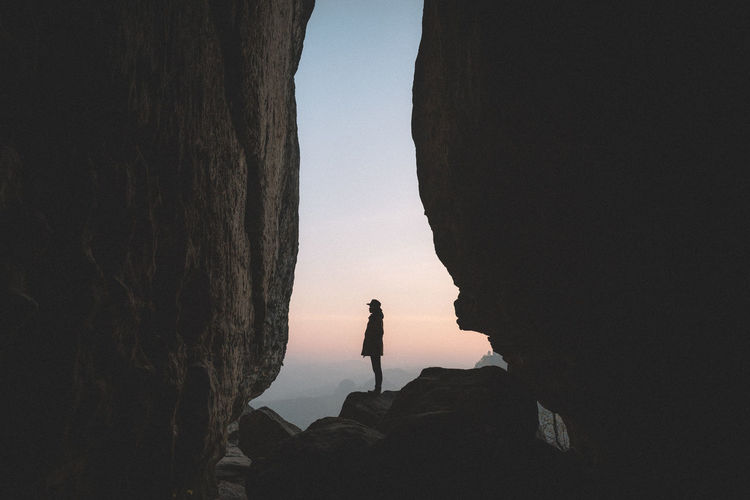 Silhouette of man standing on rock against clear sky