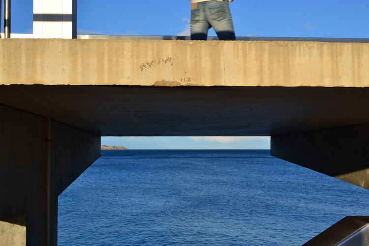 Low section of bridge over sea against clear blue sky