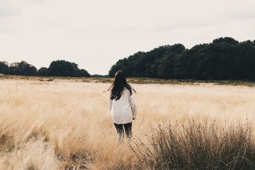 Rear view of woman standing on field against sky