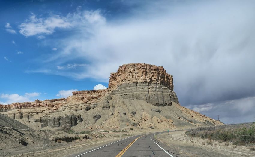 Landscape of road leading by large bare stone rounded hill in utah