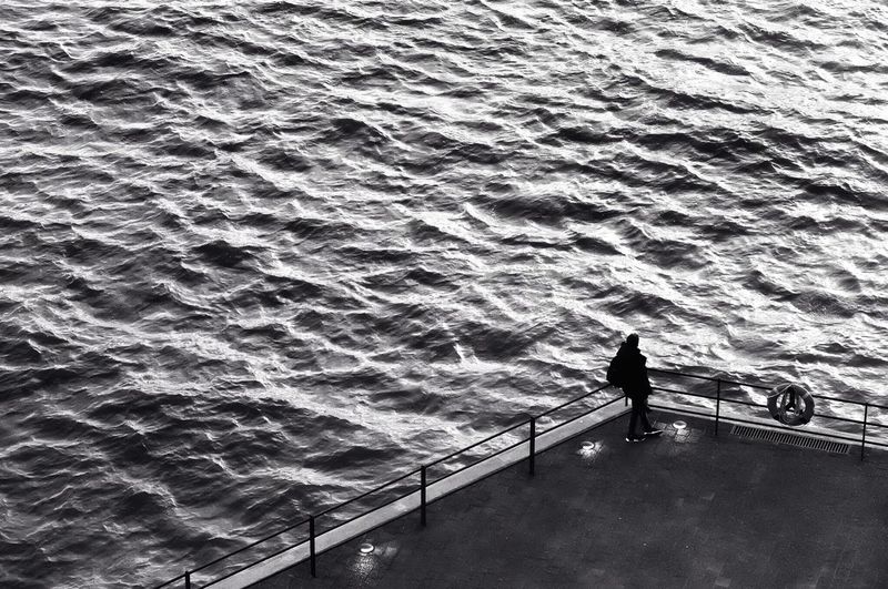 High angle view of man standing on railing by sea