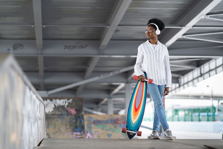 Full length of woman with skateboard standing outdoors
