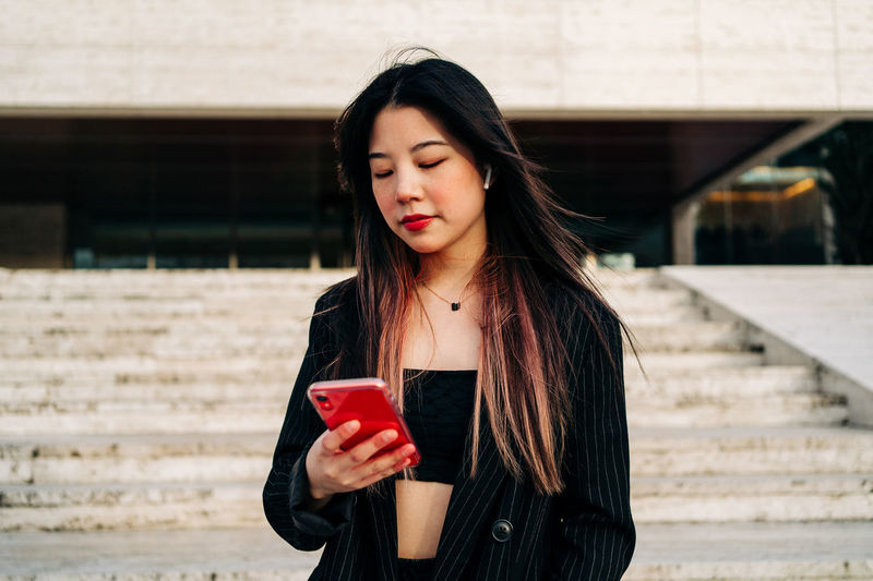 Beautiful young woman using smart phone outdoors