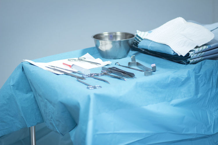Close-up of surgical tools on table against gray background