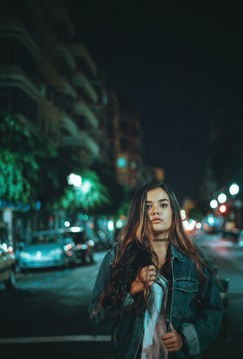 Portrait of woman standing on road at night
