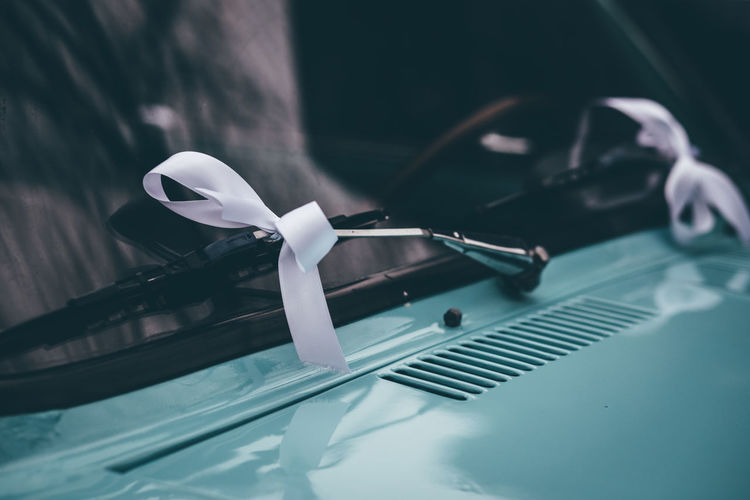 Close up of car windshield wipers with white ribbons at night