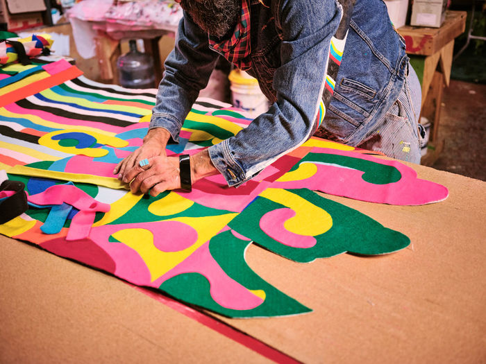 An artist works on a giant cloth tapestry in the their art studio.