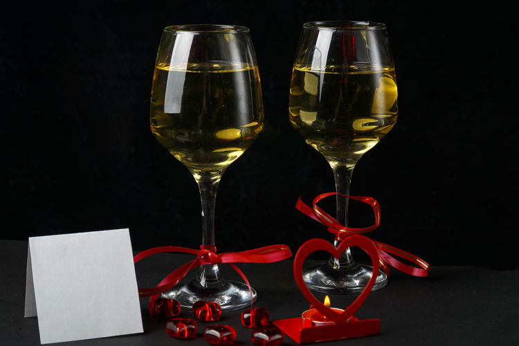 Close-up of wine glasses on table against black background