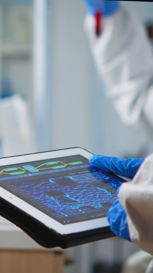 Cropped hand of doctor holding digital tablet at laboratory