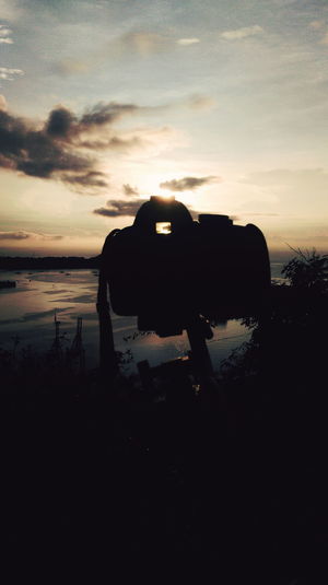 Silhouette camera against sky during sunset
