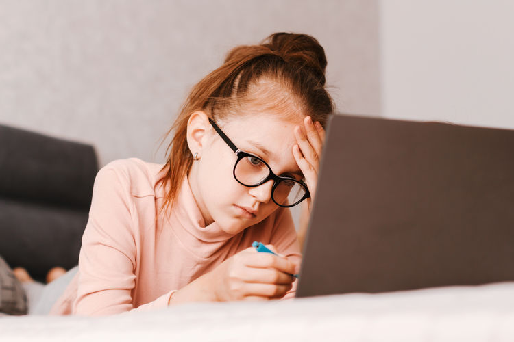 Portrait of young woman using mobile phone while lying on bed at home