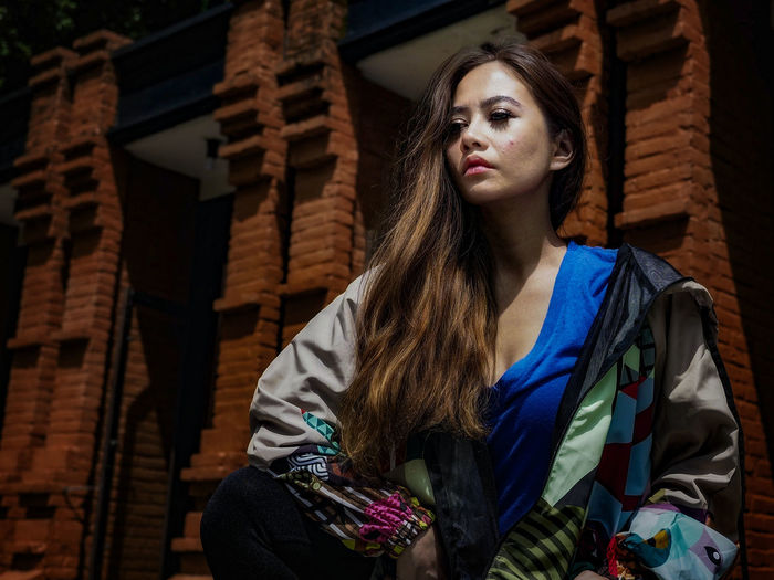 Portrait of young woman standing against wall