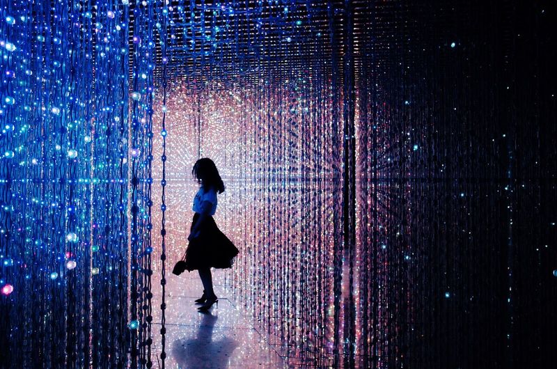 Woman standing amidst illuminated lights