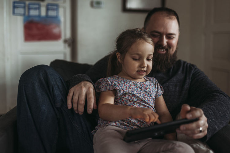 Close up of dad and young daughter playing on tablet during isolation