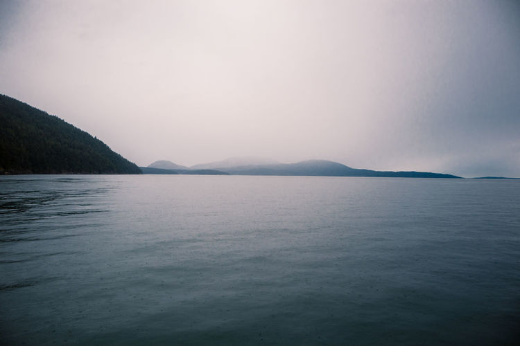 Scenic view of sea against foggy, raining sky