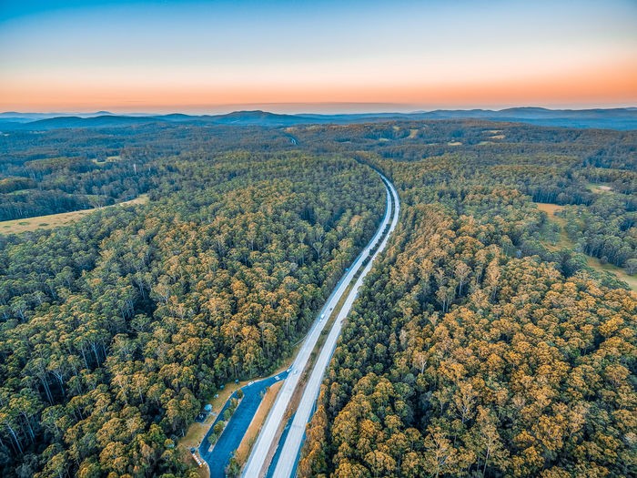 Aerial view of road amidst green landscape against sky during sunset