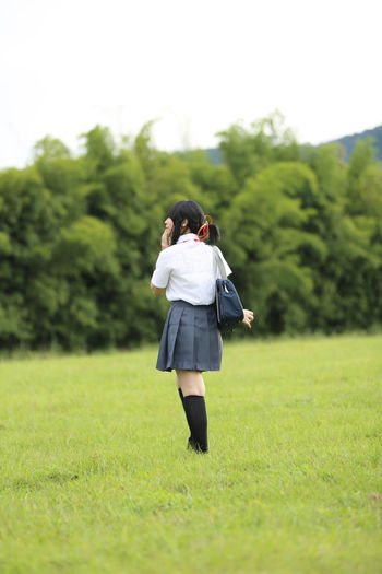 Rear view of woman in school uniform walking on field