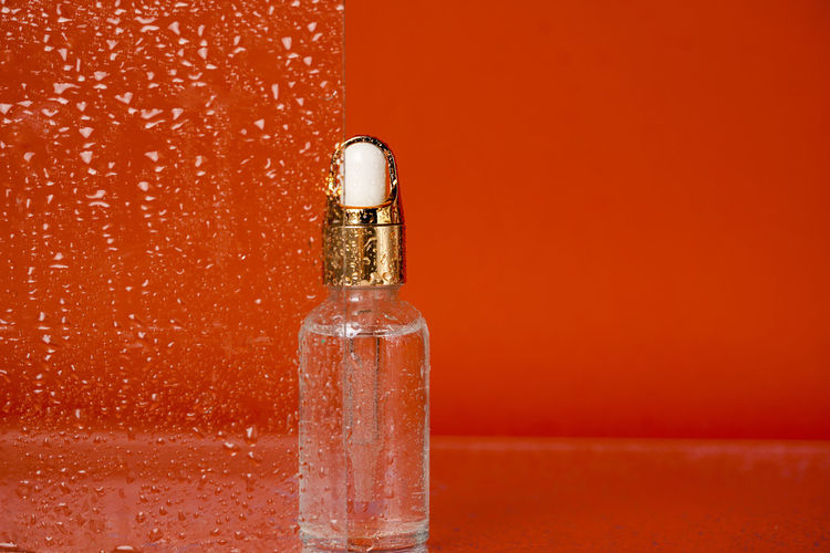 Bottle of serum with a pipette cosmetic or essential oil on a orange background 