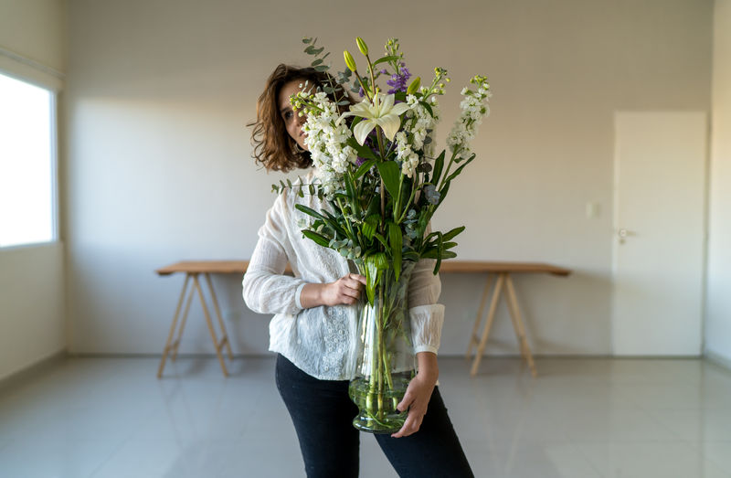 Unrecognizable model hiding her face behind bouquets of white flowers.
