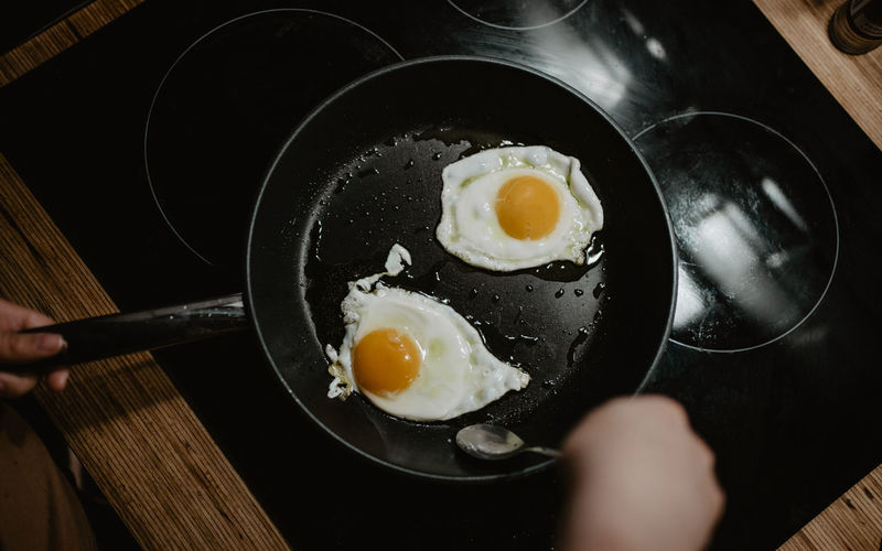 High angle view of fried eggs in pan above stove
