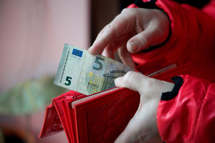 Cropped image of woman removing currency from red purse