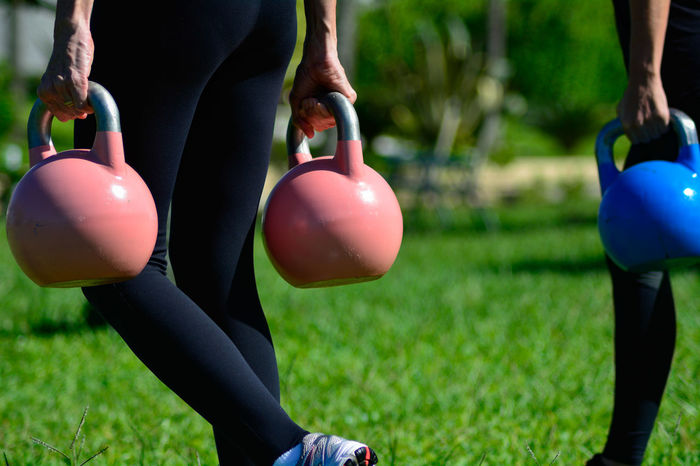 Low section of men carrying kettlebell on grass