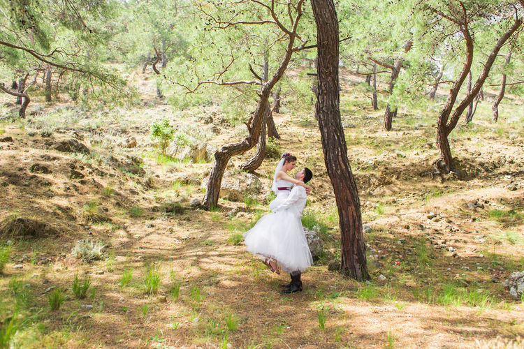 Woman standing on field by trees in forest