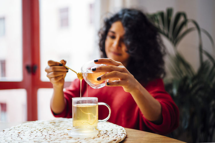 Brunette woman sweetening a tea with honey