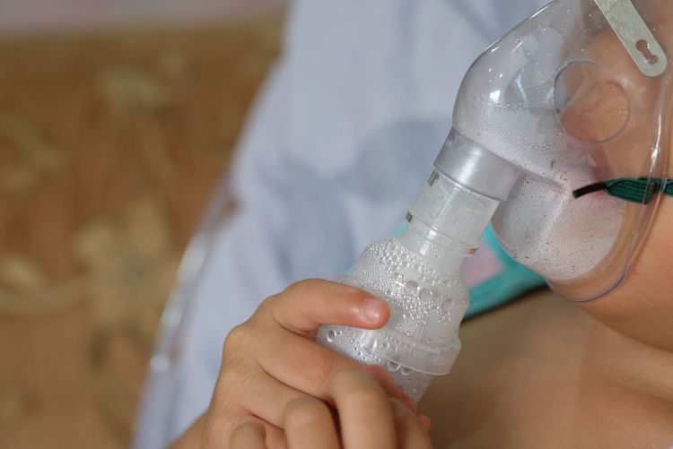 Midsection of patient inhaling through oxygen mask in hospital