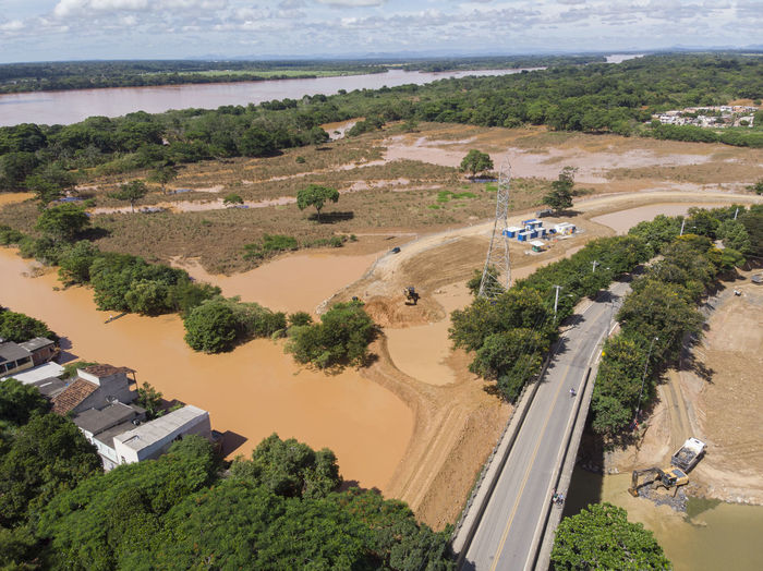 River flooding due to rain causes large mud next to a dam that prevents the rivers from meeting 