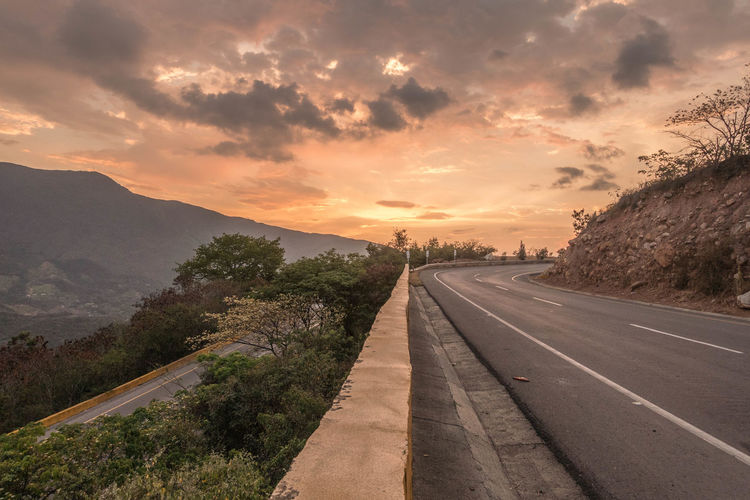 Empty road against sky during sunset