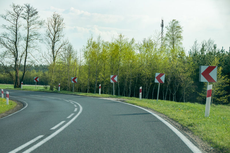 Road by trees against sky