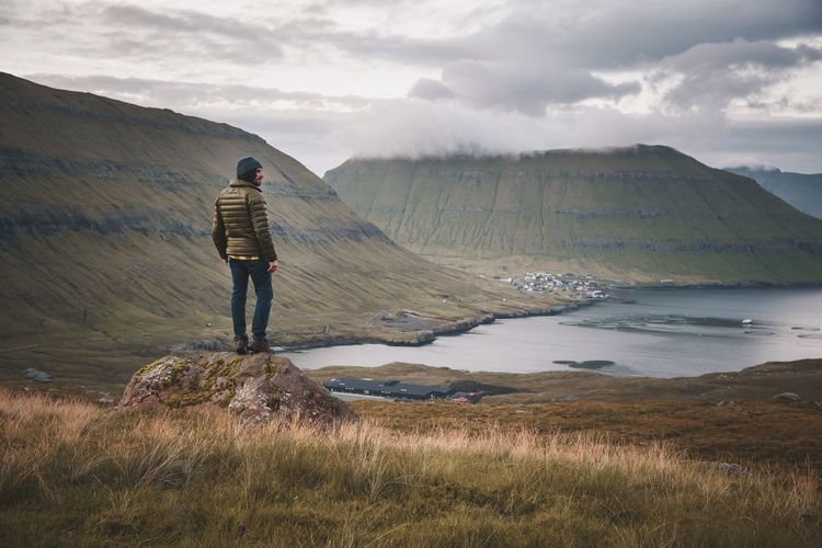 Rear view of man standing on landscape against sky