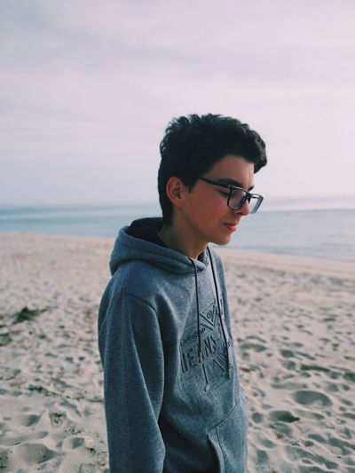 Young man wearing sunglasses standing on beach