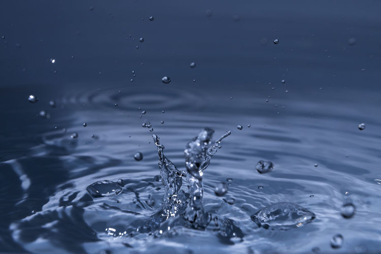 Close-up of splashing water drops causing wavy water surface