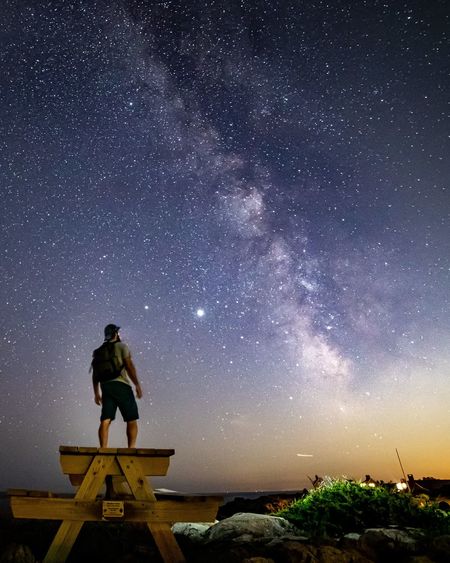 Silhouette of man star gazing on a picnic table under the milkyway.