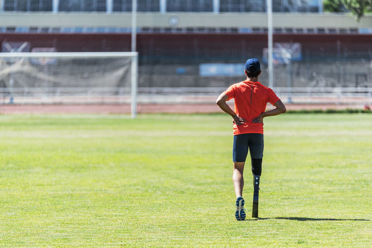 Full length of athlete with prosthetic leg standing on field