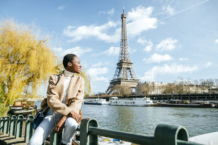 France, paris, smiling woman at river seine with the eiffel tower in the background