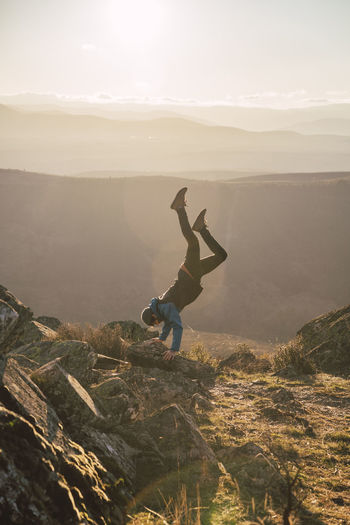 Male sportsperson exercising while doing handstand on mountain