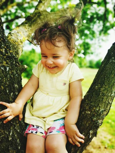 Cute girl sitting on tree trunk