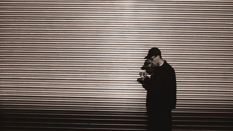 Man smoking while standing against shutter