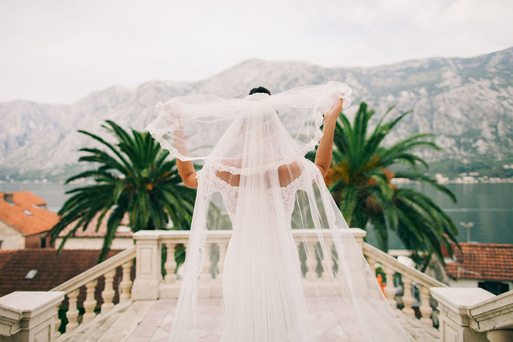 Rear view of bride holding veil at balcony