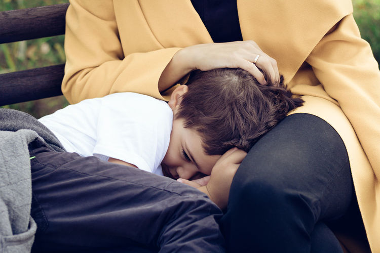 Midsection of mother with son resting on bench