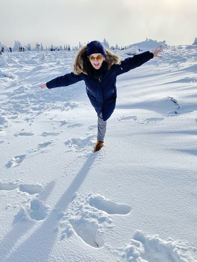 Full length of woman standing on snow covered land against sky
