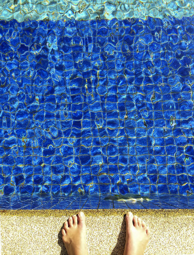 Low section of person standing by swimming pool