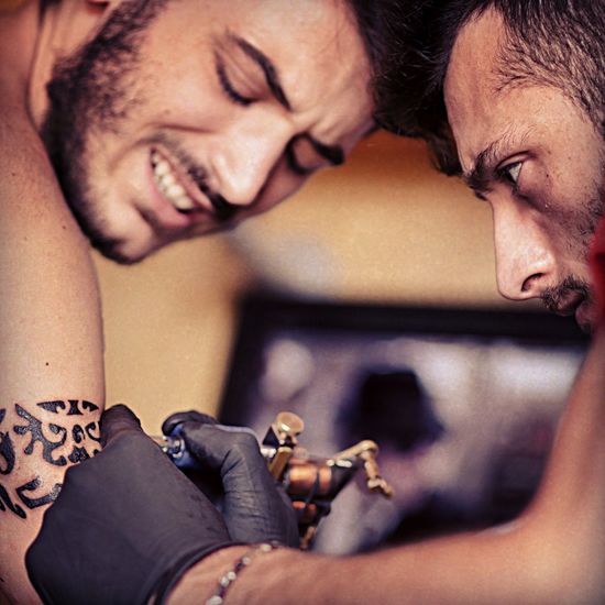 Close-up of man tattooing on customer arm