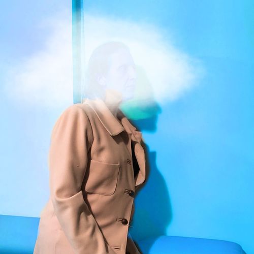 Digital composite image of cloud and woman against blue wall